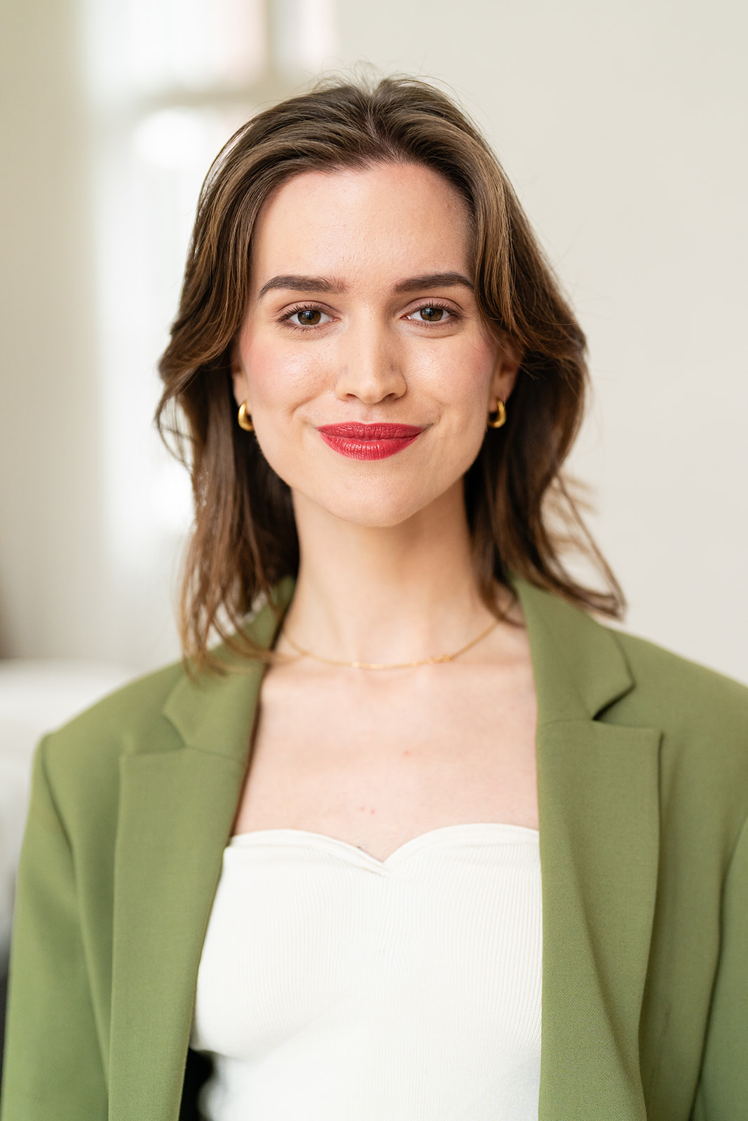 Hetzelfde model in een groene blazer met gouden sieraden en rode lipstick